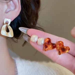 Detail showing various geometric leopard print earrings and cream square studs for daily wear