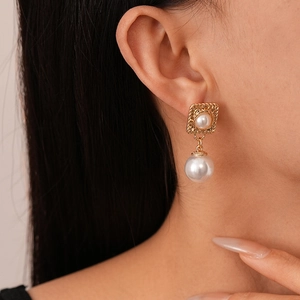 French vintage style square gold earrings with white pearls on a female model