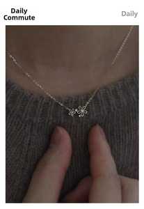 Detailed close-up of a 14K gold-plated S925 silver necklace with two small floral pendants