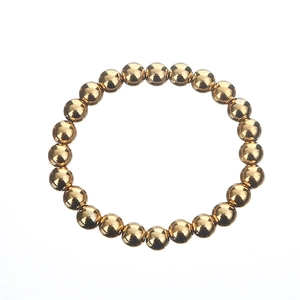 Detailed macro view of glossy gold beaded bracelet with metallic reflective surface