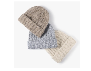 Detail of three thick bouclé knit beanies in brown, blue, and cream stacked on white