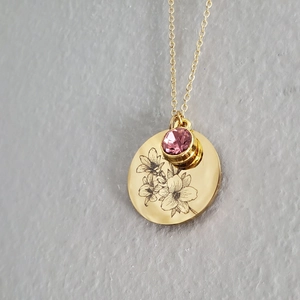 18K gold plated flower pendant necklace with pink gemstone on textured grey background