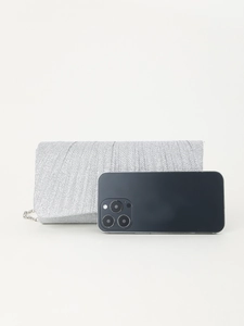 Silver glitter evening clutch bag shown next to a smartphone for size reference
