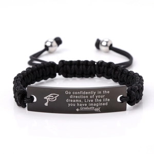 Macro detail of black braided bracelet with engraved stainless steel inspirational plate
