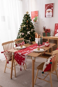 Dettaglio del runner natalizio rosso con motivi di renne bianche e nappe decorative