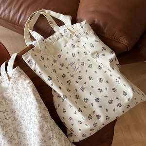 Detail of floral canvas tote bags with animal pattern patches on a vintage leather sofa