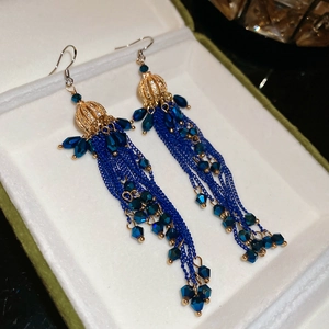 Detailed close-up of blue crystal tassel earrings with gold hollow sphere and chains