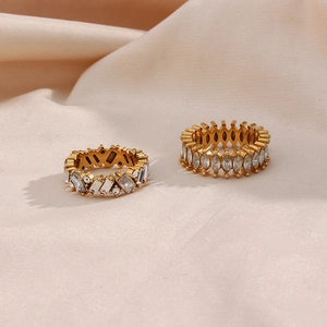 Detail of gold zircon rings featuring marquise and rectangular cut stones on beige satin