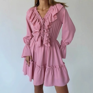 Détail d'une robe rose à col en V avec volants et lien décoratif sur le buste élégant