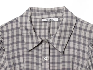 Close-up of the grey and white plaid dress collar with button detail and ZEDeRI label