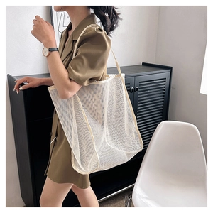 Detalle de bolso tote de malla crema con forro de leopardo mostrado por una modelo