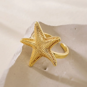 Minimalist 18K gold starfish open ring with realistic texture on a stone pedestal