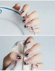 Detailed macro of 5D nail art stickers with black butterflies and small white pearls