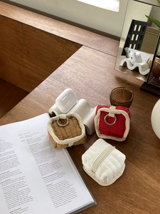 Three corduroy mini earphone pouches in white, red and khaki on a wooden table