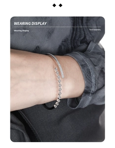 Macro detail of silver geometric bangle with square diamond pattern on a female wrist