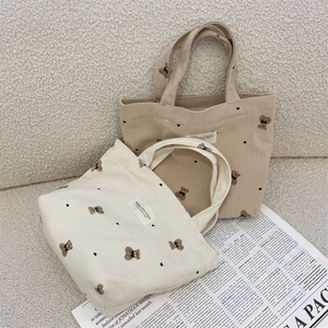 Close-up of corduroy tote bags with bear patch and heart prints on textured background