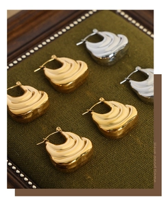 Detailed view of gold and silver textured earrings on a premium velvet display stand