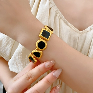 Close-up of vintage gold bracelet with black geometric links on woman wrist