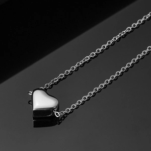 Macro shot of silver heart pendant charm with polished finish on reflective black background