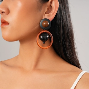 Détail de boucles d'oreilles rétro avec perles en bois et anneaux orange sur modèle