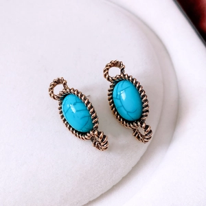 Detailed macro view of vintage bronze oval earrings featuring inlaid blue turquoise stones