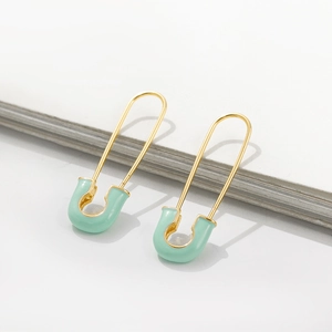 Detailed view of mint green enamel safety pin earrings with a polished gold finish