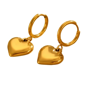 Detail von polierten goldenen Herzanhänger-Ohrringen mit glänzendem Finish auf weißem Grund