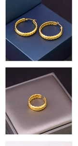 Detailed texture of gold woven hoop earrings and ring displayed on gift boxes