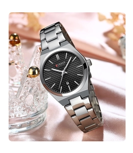 Detail of silver steel ladies watch with black dial and calendar resting on crown