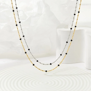 Minimalist gold and silver beaded necklaces on a white geometric background
