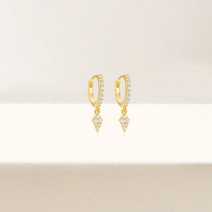 Macro detail of S925 sterling silver hoop earrings with gold finish and zircon rhombus pendant