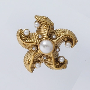 Close-up of golden starfish earrings with polished white pearls and vintage textures