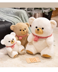Three plush teddy bears with red plaid scarves in different sizes on a soft rug