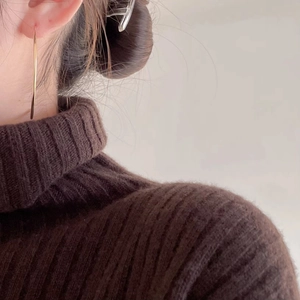 Close-up of minimalist gold ripple hoop earring worn with brown knit sweater