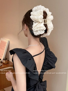 Detail of a large white layered fabric bow hair claw clip styled on a model bun