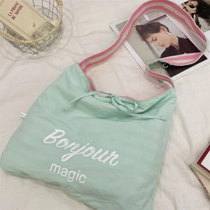Detail of mint green canvas tote bag with Bonjour magic text and striped woven strap