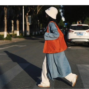 Vibrant orange large capacity nylon tote bag shown in a street lifestyle setting