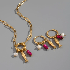 Details von goldenen Halsketten und Fischohrringen mit rosa Perlen und Edelsteinen