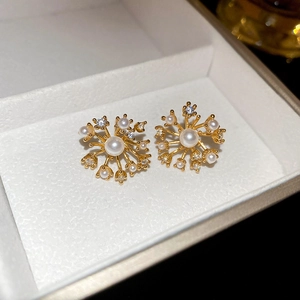 Macro shot of gold firework stud earrings with pearls and zircon in a white gift box