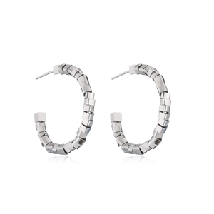 Macro shot of silver C-shaped hoop earrings with geometric cube stitching design