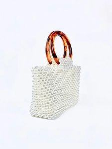 Elegant handmade pearl woven handbag featuring amber resin ring handles on a white background