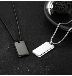 Polished silver and black rectangle dog tag pendants on snake chains over dark background