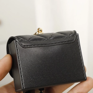 Detail of black quilted mini coin purse with gold zipper and premium leather texture