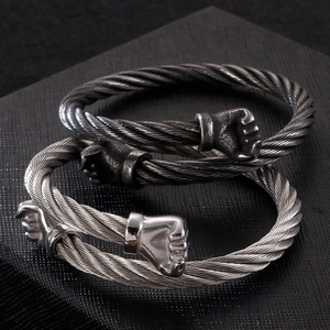 Detailed close-up of two twisted steel wire bracelets with fist charms in silver and black