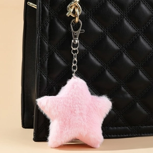 Detailed close-up of a soft pink plush star charm attached to a quilted leather bag