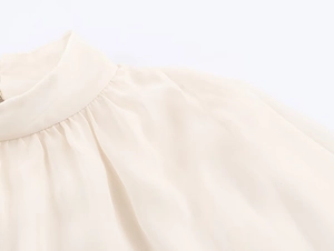 Detail of elegant high collar and pleated shoulder on cream chiffon blouse
