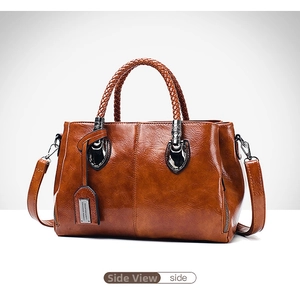 Side view of dark brown oil wax leather Boston bag with woven handles and metal charm