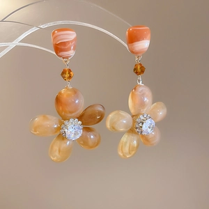 Macro shot of resin flower earrings with marble texture and sparkling crystal center