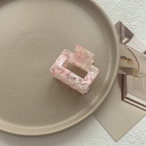 Dettaglio molletta per capelli in acetato marmorizzato rosa su vassoio in ceramica