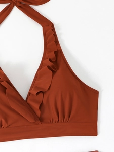 Dettaglio del top bikini halter rosso mattone con volant e scollatura a V profonda